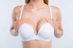 Cropped close up of woman wearing a white bra with breast augmentation with implants